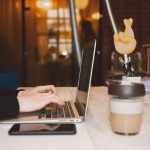 Person typing on laptop with coffee cup, symbolizing freelance virtual assistant support for solopreneurs.